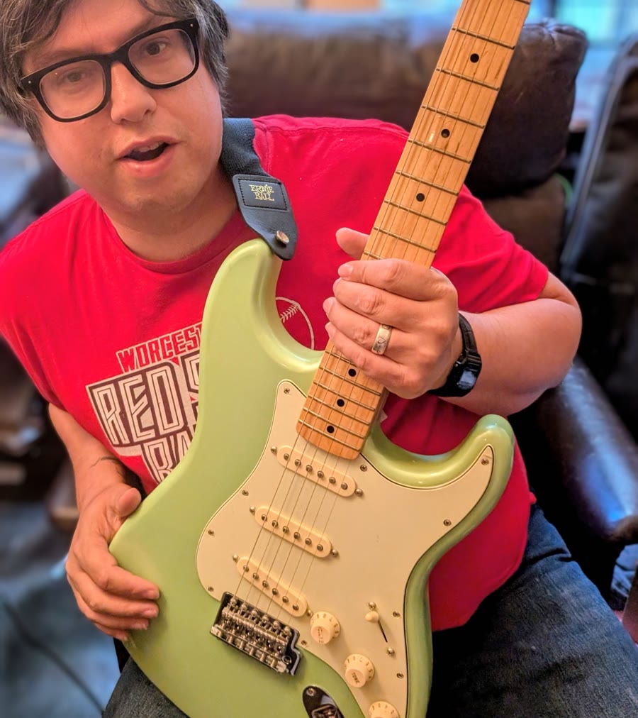 Travis Briggs holding a surf-green Stratocaster